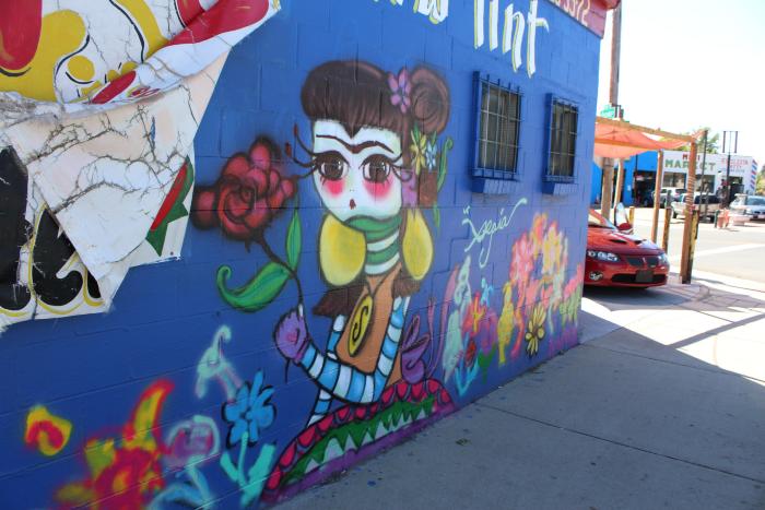Untitled (figurine of a girl on a bright blue field surrounded by bright colors and flowers)