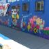 Untitled (figurine of a girl on a bright blue field surrounded by bright colors and flowers)